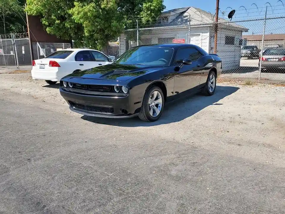Black Dodge Challenger with a clean, glossy finish parked outside after repair