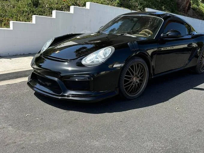 Black Porsche Cayman with a glossy finish parked on the street after its repair