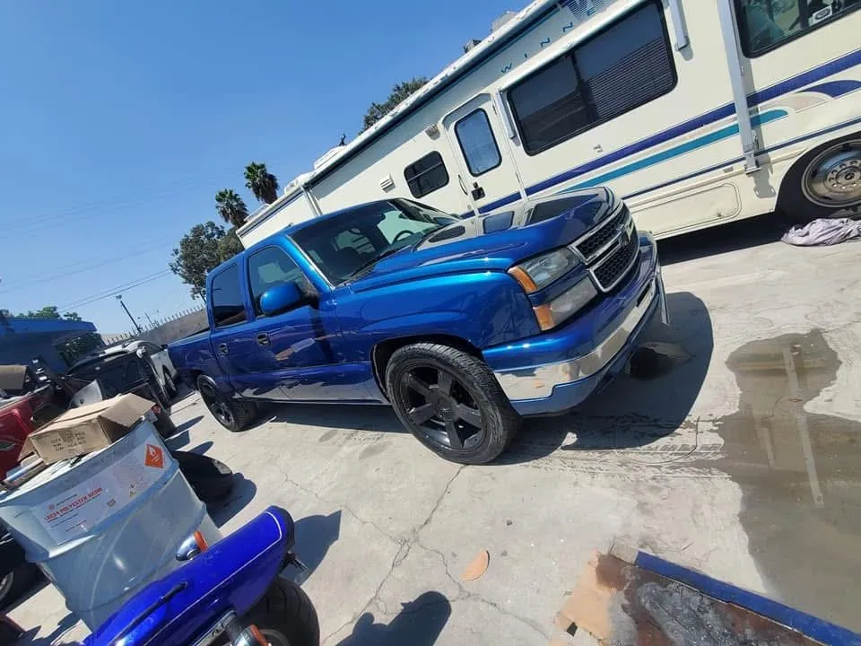 Blue Chevrolet Silverado pickup with a fresh, glossy paint job in the shop yard