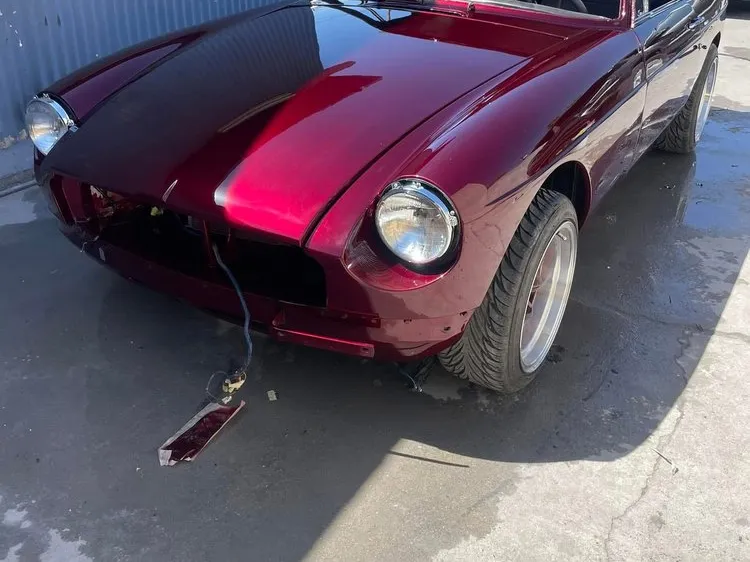 Classic MG coupe in a deep burgundy paint job, waiting for its grille and trim