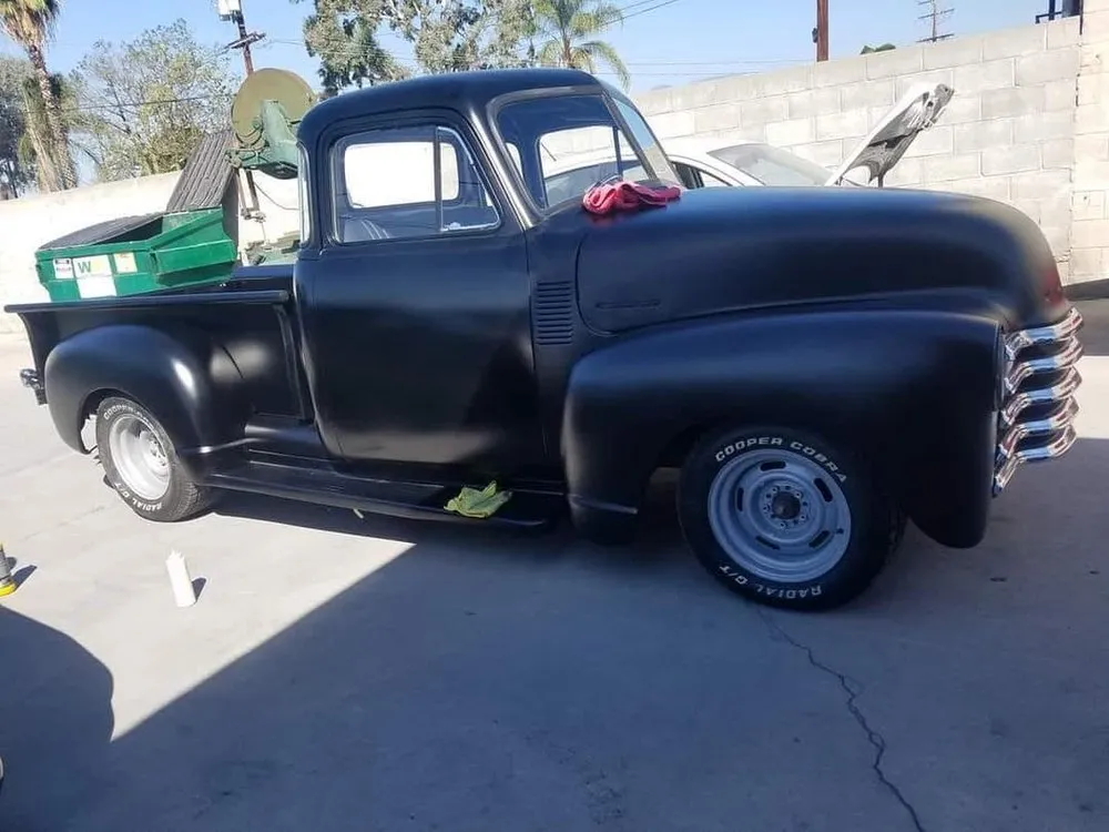 Classic Chevrolet pickup truck refinished in satin black, parked in the shop yard