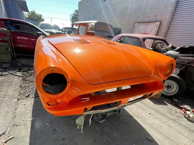 Classic roadster body in bright new orange paint, ready for its lights and trim
