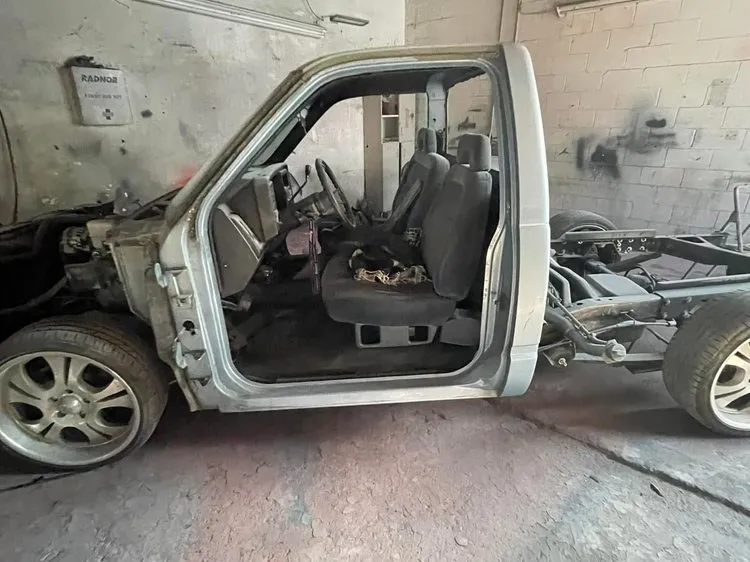 Pickup truck cab stripped to bare metal on its frame during restoration