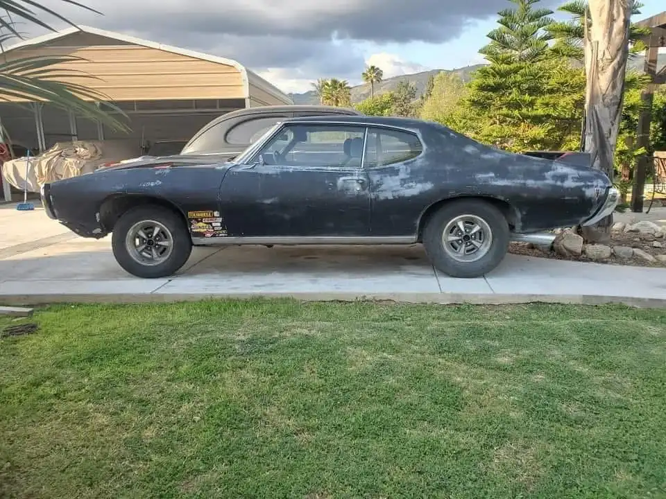 Classic Pontiac GTO in worn black paint and primer before its restoration