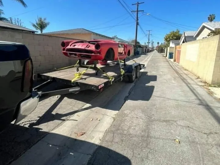 Red classic roadster body on a trailer, arriving for restoration work