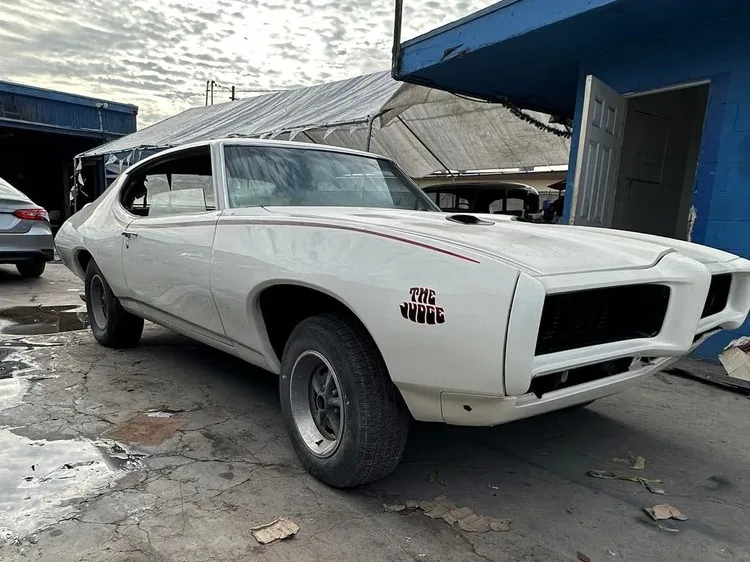 White Pontiac GTO Judge with red pinstripes in the shop yard during restoration